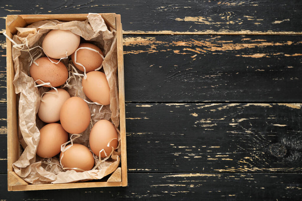 Caja con huevos de pollo sobre fondo de madera
 - Foto, Imagen