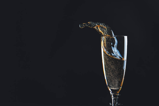 Glas champagne met splash op donkere achtergrond - Foto, afbeelding