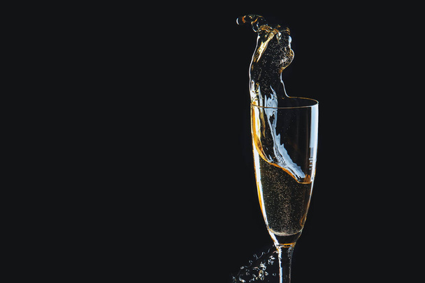 Glass of champagne with splash on dark background - Photo, Image