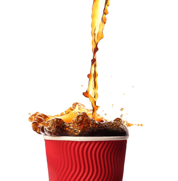 Χύσιμο του ζεστού καφέ σε φλιτζάνι σε λευκό φόντο - Φωτογραφία, εικόνα