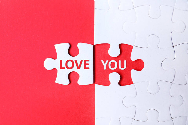 White puzzle with separated piece and phrase LOVE YOU on red background, top view - Foto, Imagem