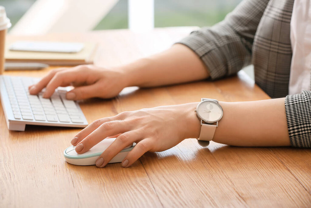 Frau benutzt PC-Maus, während sie am Computer am Tisch arbeitet, Nahaufnahme - Foto, Bild