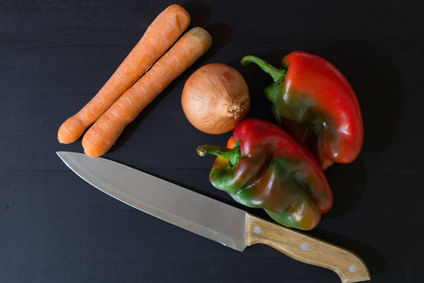 λαχανικά και μαχαίρι σε μαύρο ξύλο - Φωτογραφία, εικόνα