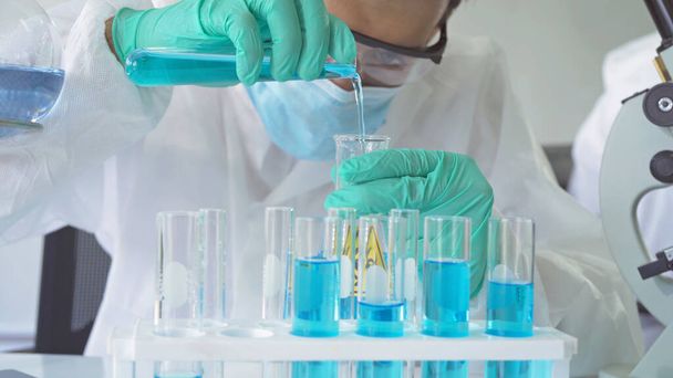 アジアの科学者は、技術医学、化学、医療、研究コンセプトの研究室や研究室で、 covid-19ウイルスのワクチンの分析と開発のための青い試験管に取り組んでいます。実験科学 - 写真・画像