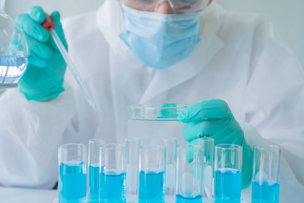 Asian Scientist trabaja en tubo de ensayo azul para analizar y desarrollar la vacuna del virus covid-19 en laboratorio o laboratorio en tecnología médica, química, salud, concepto de investigación. Ciencias experimentales
 - Foto, imagen