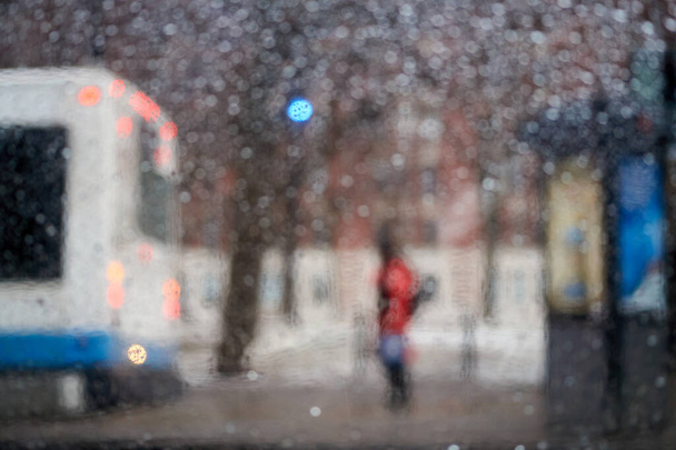 Persone alla fermata di un autobus in una serata piovosa, immagine astratta offuscata con luci dell'auto. - Foto, immagini