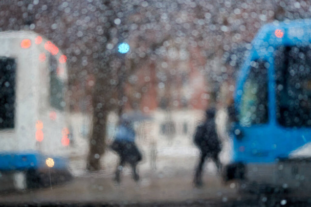 Persone alla fermata di un autobus in una serata piovosa, immagine astratta offuscata con luci dell'auto. - Foto, immagini