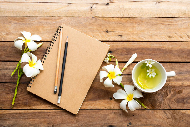 Планувальник ноутбуків для ділової роботи з трав'яними здоровими напоями лимонад, білі квіти франгіпані розташування плоский стиль на фоні дерев'яного
 - Фото, зображення