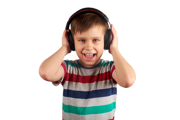 Child listens to his favorite music on headphones and dances to it , isolated on white background. Leisure, music and entertainment concept. - Photo, image
