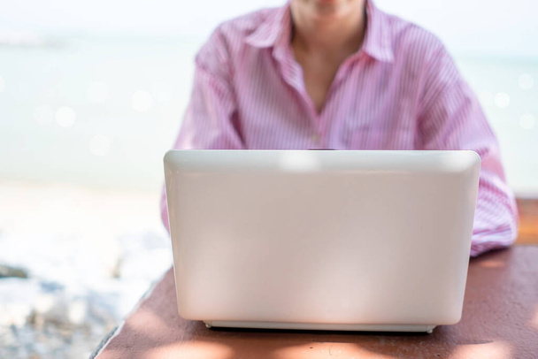 Vrouw hand met behulp van laptop om te studeren op het werk bureau met schone natuur strand outdoor achtergrond. Bedrijfs-, financiële, handelsvoorraad en sociaal netwerk concept. - Foto, afbeelding