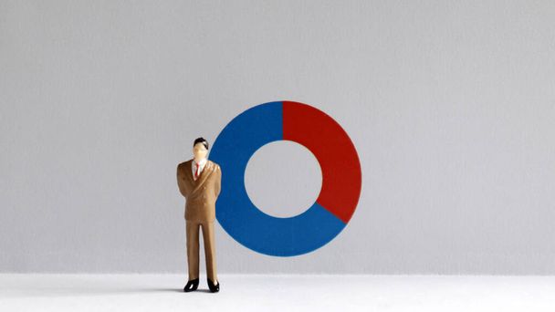 A miniature man standing in front of a donut graph. - Foto, Bild