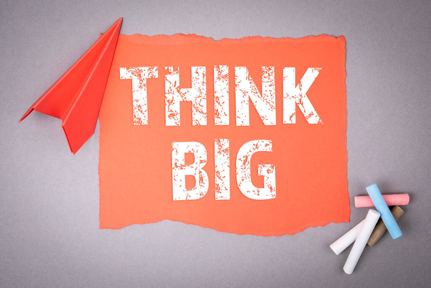THINK BIG. Motivation and inspiration concept. Text on note sheet, paper plane, symbol of gaining goals - Photo, Image