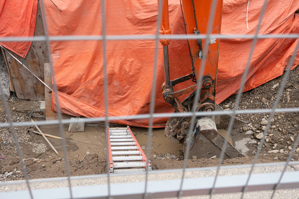 Agujero de excavación detrás de una cerca de malla de alambre en un sitio de construcción del centro de la ciudad
 - Foto, Imagen