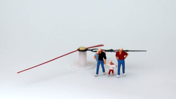 Same-sex marriage concept. A miniature family walking toward the hands of a clock. - Photo, Image