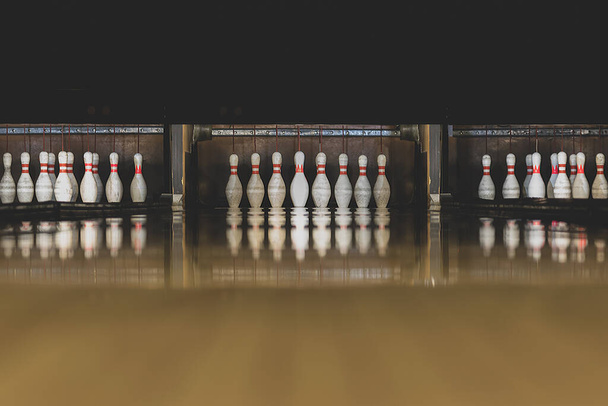 Leisure, entertainment and activities concept. Abstract background with copy space of old and dark parquet bowling track with white pins at the end of it - Foto, immagini