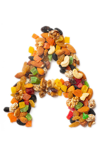 Letter A of the English alphabet from a mixture of hazelnuts, almonds, walnuts, cashews, seeds, raisins, candied fruit on a white isolated background. Food pattern made from nuts.  - Photo, Image