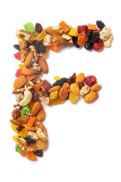 Γράμμα F του αγγλικού αλφαβήτου από μείγμα φουντουκιών, αμυγδάλων, καρυδιών, κάσιων, σπόρων, σταφίδων, ζαχαρωτών φρούτων σε λευκό απομονωμένο φόντο. Μοτίβο τροφίμων από ξηρούς καρπούς.  - Φωτογραφία, εικόνα