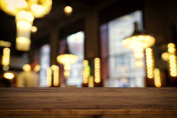 background Image of wooden table in front of abstract blurred restaurant lights - Photo, image
