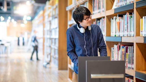 Fiatal ázsiai férfi egyetemi hallgató tolja könyv kosár főiskolai könyvtár megtalálása tankönyv oktatási kutatás. Bestseller gyűjtemény a könyvesboltban. Ösztöndíj vagy oktatási lehetőség fogalmai - Fotó, kép