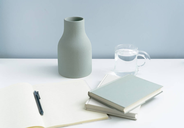 Minimalistisch boekje en eenvoudige vaas op tafel gelegd. Off-white ruimte premium meubilair  - Foto, afbeelding
