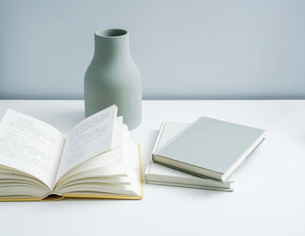 テーブルの上に置かれたミニマリストブックノートとプレーン花瓶。白以外のスペースプレミアム家具  - 写真・画像