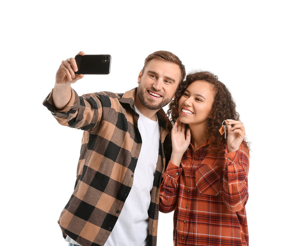 Onnellinen nuori pari avaimella ottaen selfie valkoisella taustalla - Valokuva, kuva