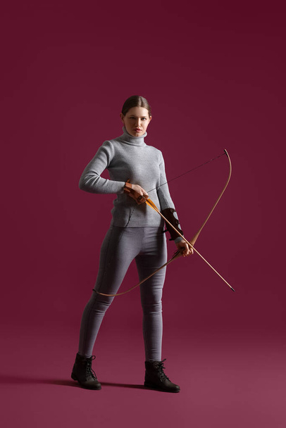 Beautiful woman with crossbow on color background - Foto, afbeelding