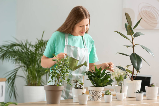 fiatal nő öntözés növények otthon - Fotó, kép