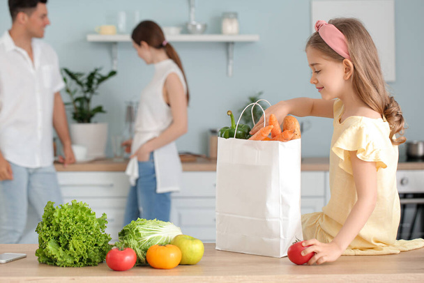 Kleines Mädchen packt in Küche frische Produkte vom Markt aus - Foto, Bild