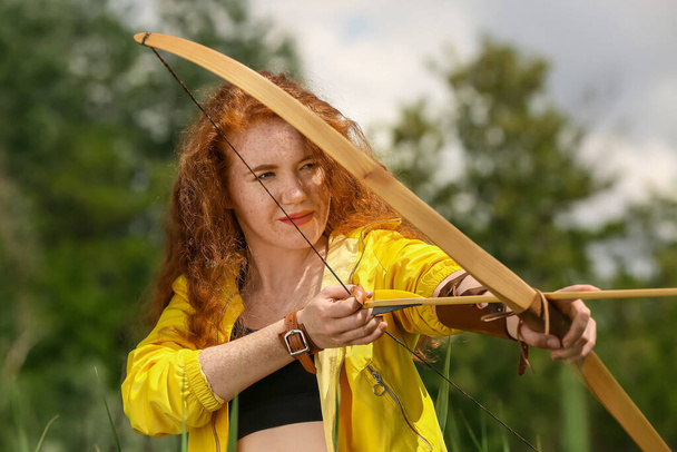 Mujer joven y deportiva practicando tiro con arco al aire libre
 - Foto, imagen