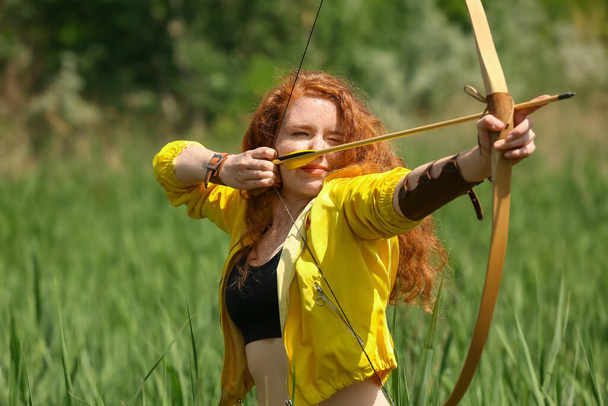 Sporty young woman practicing archery outdoors - Photo, Image
