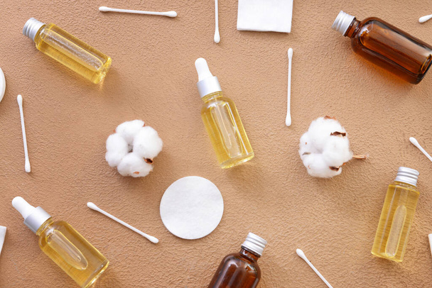 Bottles of cottonseed oil with cosmetic pads and swabs on color background - Photo, Image