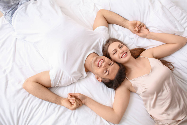 Morgen eines glücklichen jungen Paares, das im Bett liegt - Foto, Bild