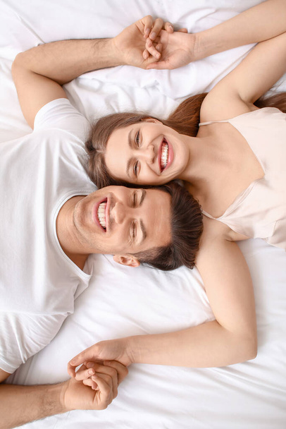 幸せな若いカップルの朝のベッドに横たわって - 写真・画像