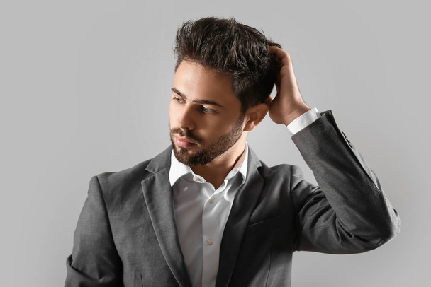 Handsome man with stylish hairdo on grey background - Foto, imagen