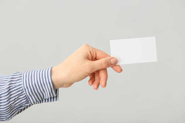 Female hand with blank business card on light background - Photo, Image