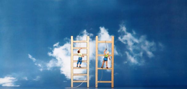 Escaladores en miniatura escalando una escalera de madera contra el fondo del cielo azul
.  - Foto, imagen