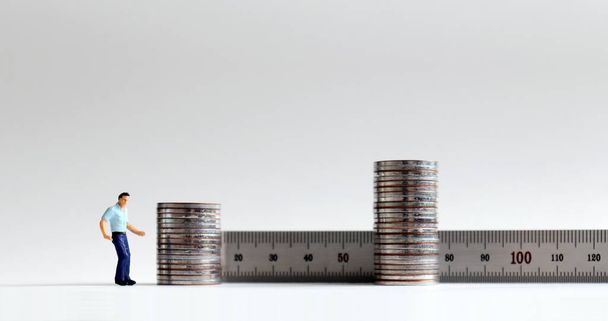 Concept d'augmentation des coûts de main-d'œuvre. Personnes miniatures avec deux piles de pièces. - Photo, image