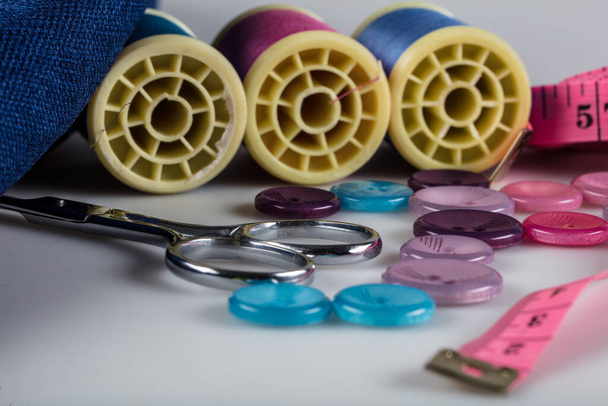 Kit de costura: tijeras, cinta métrica, dedal, hilos y botones. Tijeras, bobinas con hilo y agujas, tela
. - Foto, Imagen