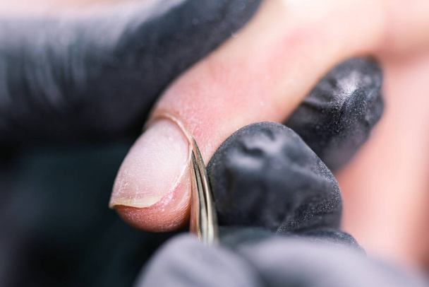 Zbliżenie na manicure sprzętowy w salonie piękności. Manikiurzystka stosuje elektryczne wiertarki do paznokci do manicure na kobiecych palcach. - Zdjęcie, obraz