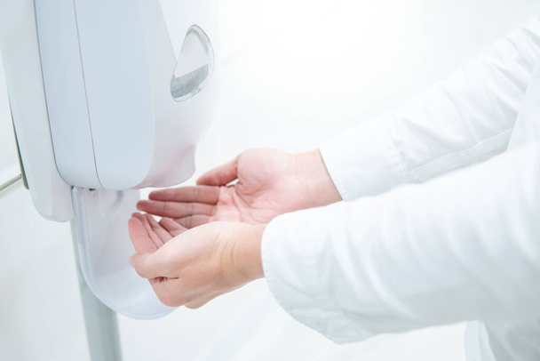 Male patient hands using automatic alcohol dispenser for cleaning hand in hospital. Infection prevention concept. Save and clean in public medical center area. - Fotoğraf, Görsel