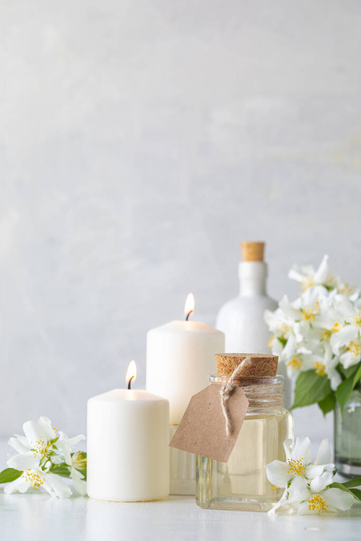 Home spa resort: jasmine essential oil, candles and flowers on a white background. Spa and wellness concept - Foto, Imagem