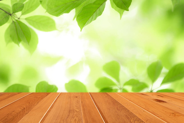 Dřevěný stůl top na rozmazat abstraktní zelený list ze zahrady v ranním pozadí. - Fotografie, Obrázek