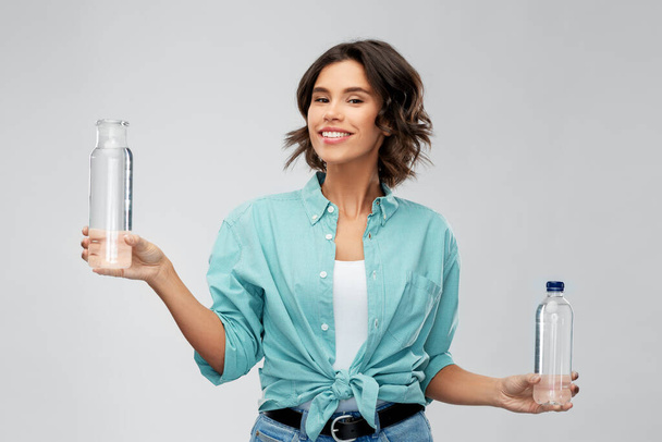 smiling young woman comparing bottles of water - Φωτογραφία, εικόνα
