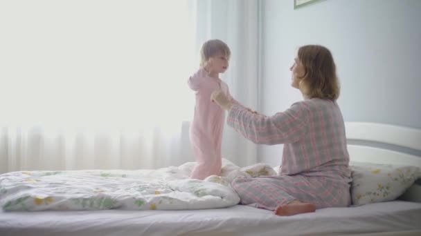 A kislány megöleli a terhes anyját. Anya és a baba a hálószobában az ágyon. - Felvétel, videó