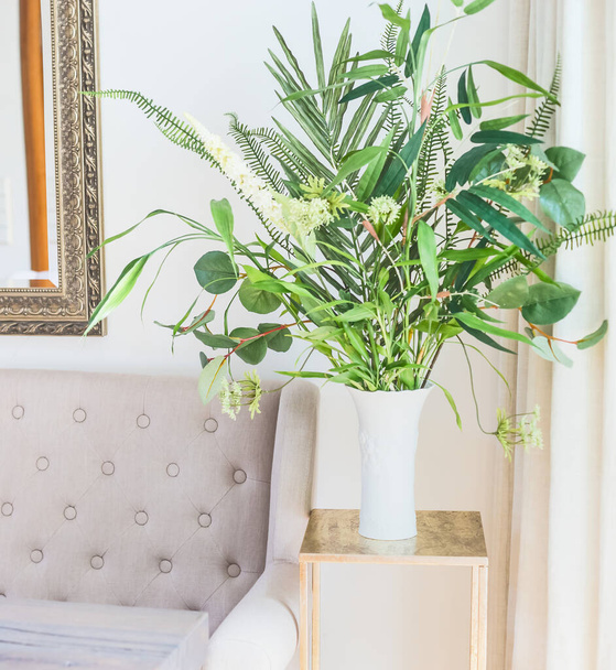 Green tropical  houseplants bunch in vase near the couch in luxury living room. Home decoration and interior - Foto, Bild