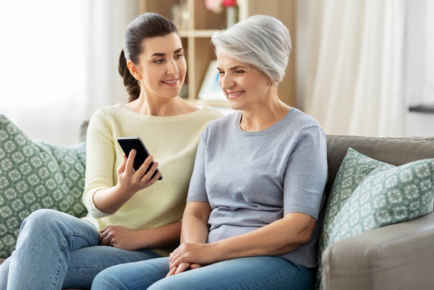 daughter and senior mother with smartphone at home - Foto, Imagen