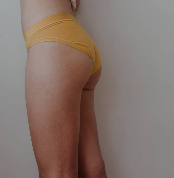 vrouw heupen in geel lingerie - Foto, afbeelding