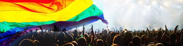 虹の旗を持つゲイやレズビアンのパレードのシルエット-愛と寛容の象徴 - 写真・画像