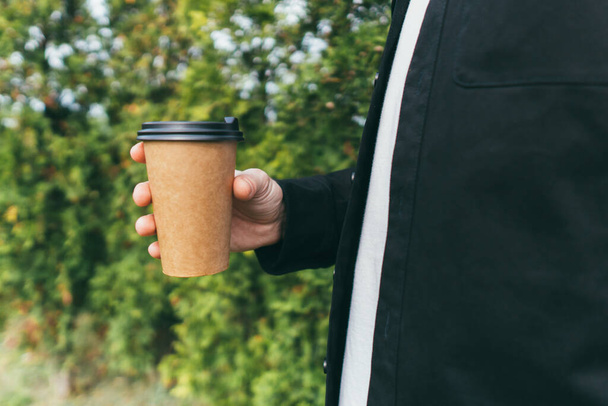 カフェの外でコーヒーを飲みながらコーヒーを楽しむ魅力的な男 - 写真・画像